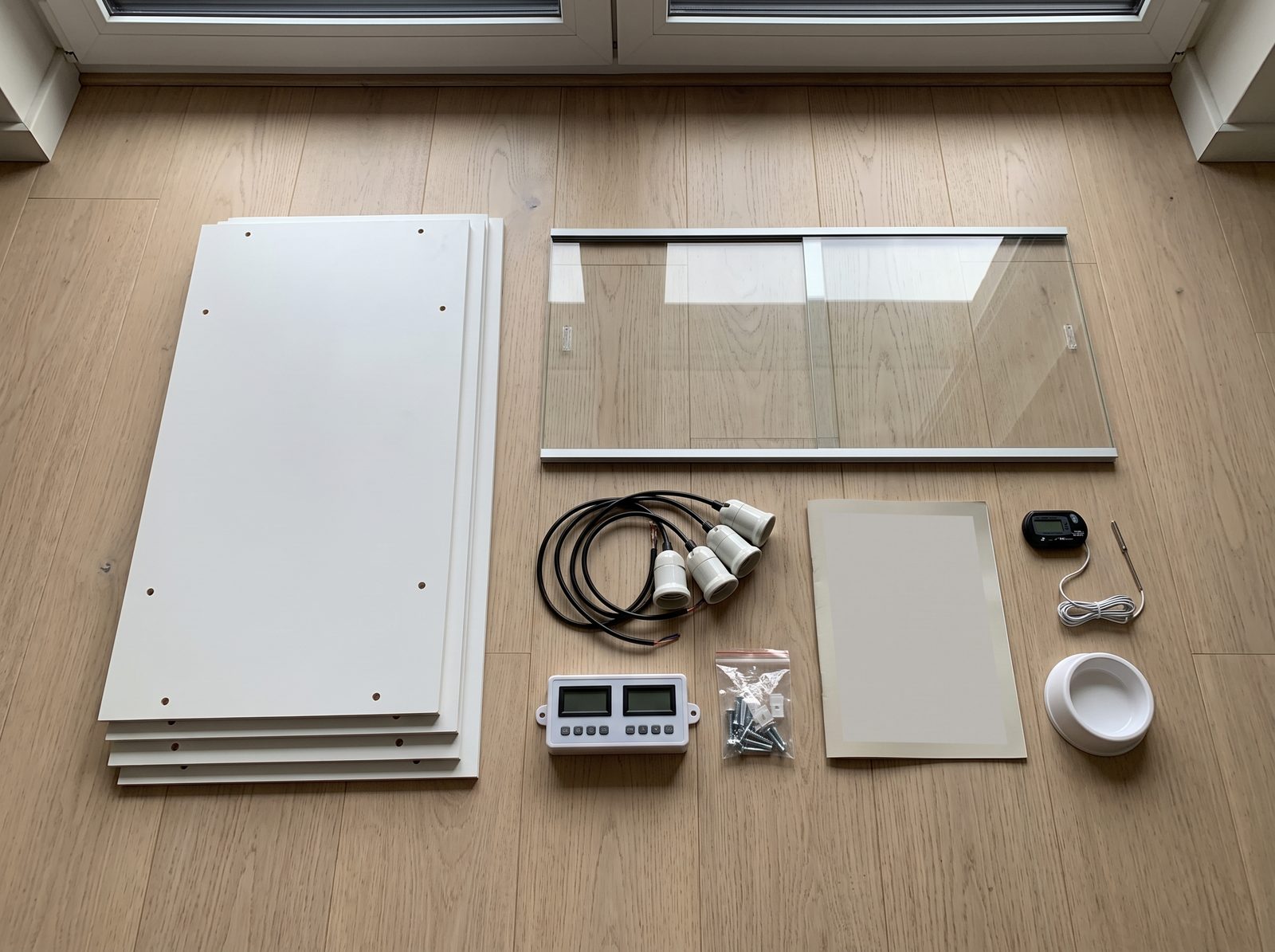 Le contenu du carton pose a plat : panneaux, vitre et son rail, douilles ceramique, module thermostat, visserie, notice, thermometre et gamelle