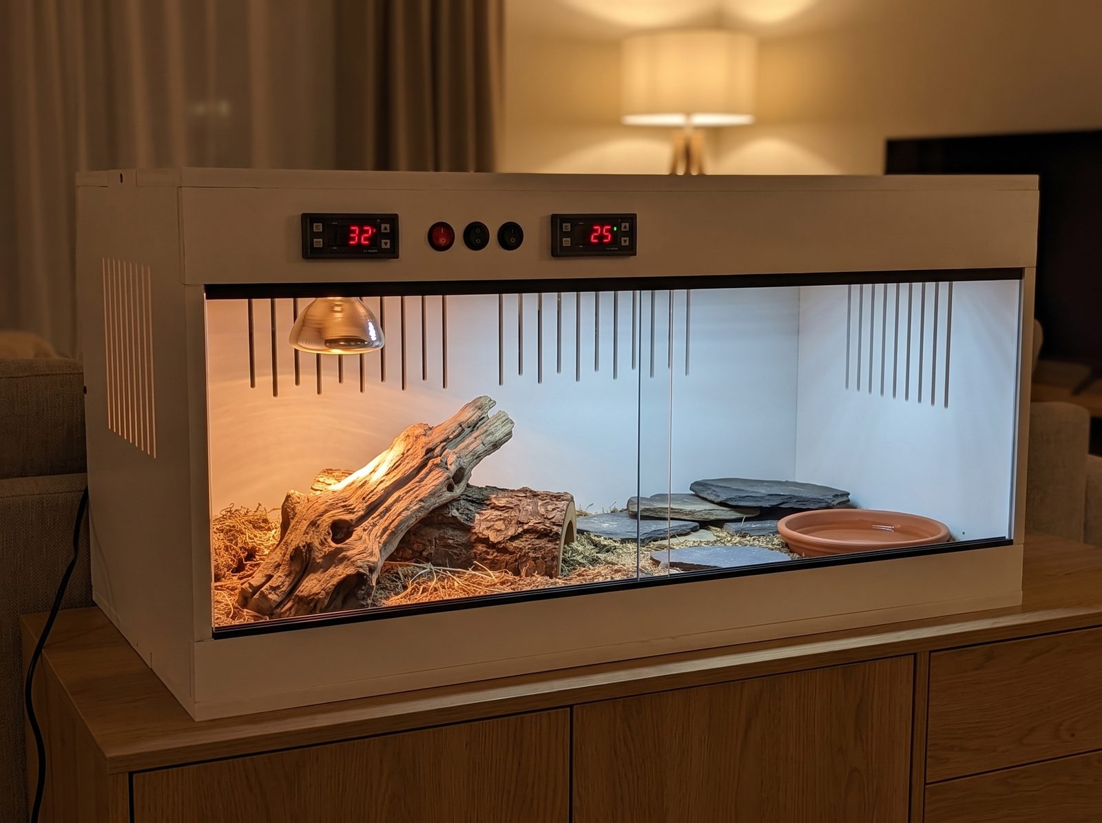 Le terrarium termine et amenage sur un meuble, les deux ecrans du thermostat allumes